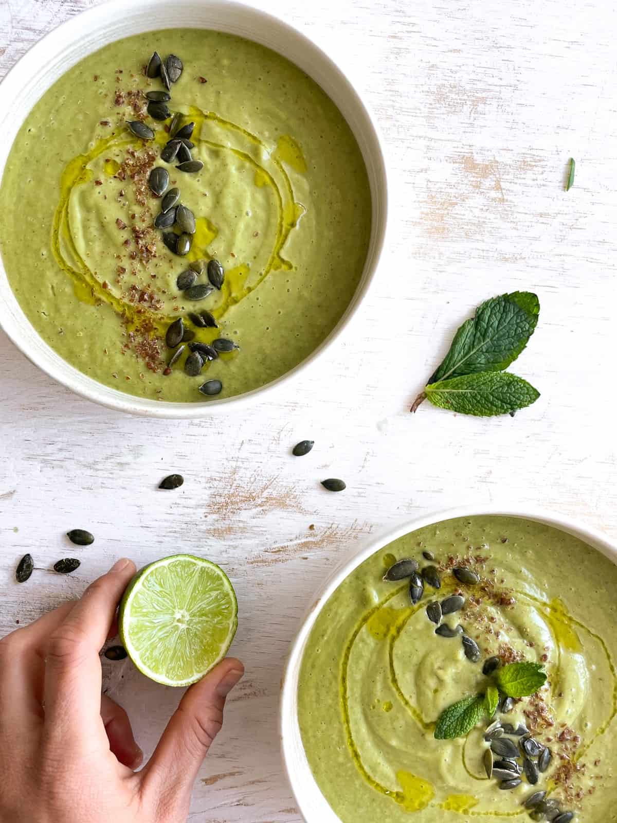 Two bowls of chilled creamy cucumber soup with seeds on top