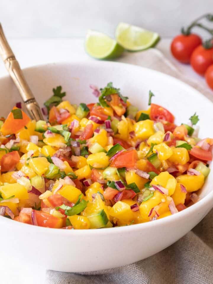 Mango cucumber salsa in a bowl, with a spoon in it - square