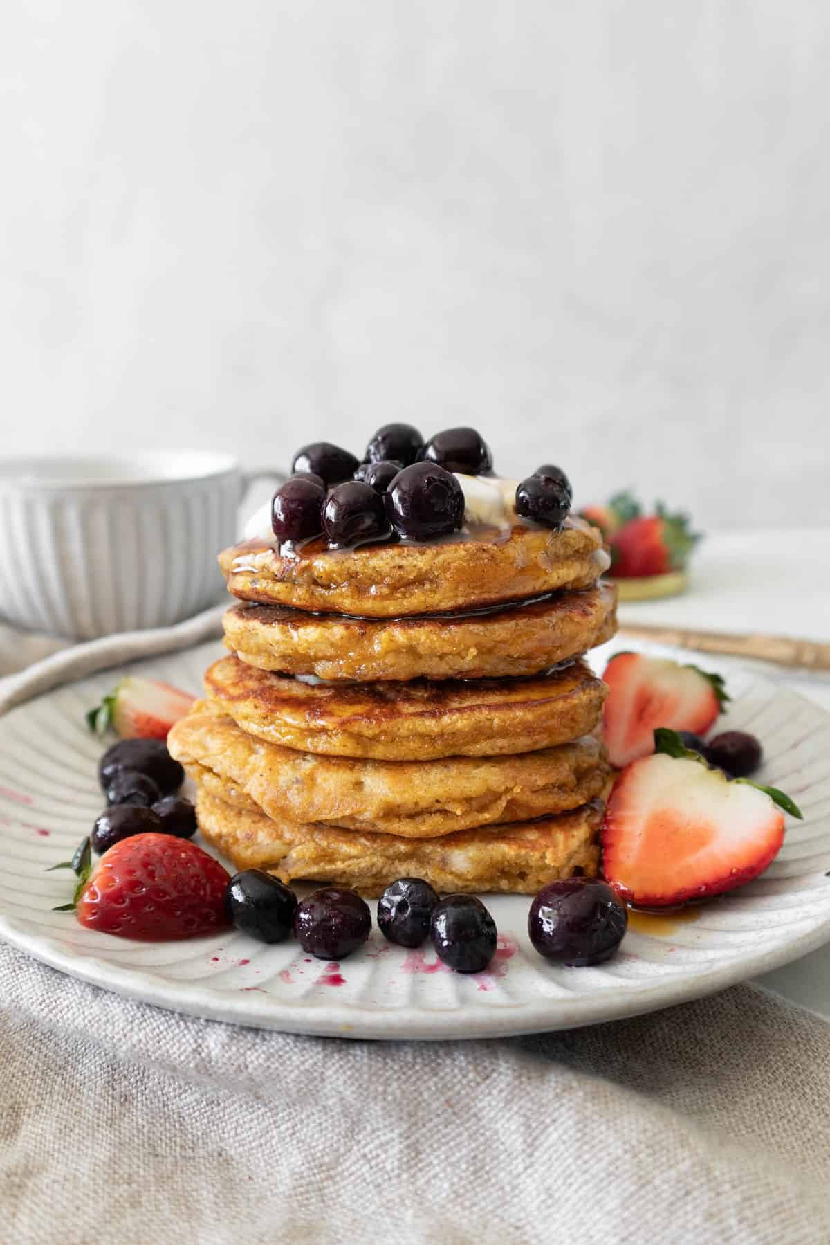 stack of coconut flour banana pancakes with coconut yogurt and berries