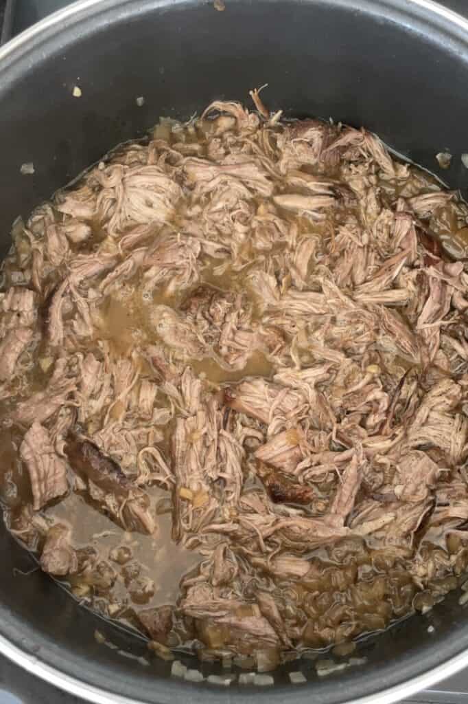 Pulled BBQ beef brisket mixing pulled meat with onion and stock