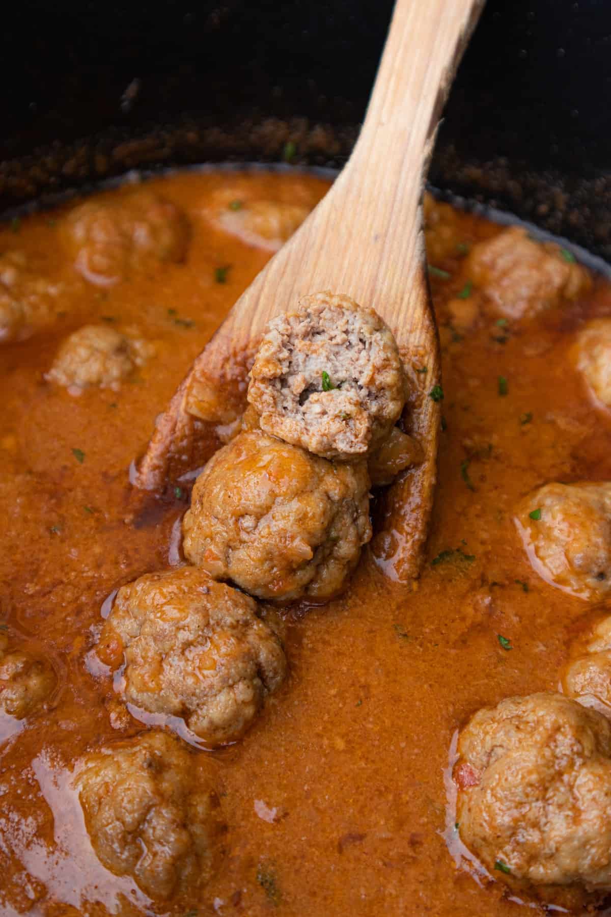 Close up of gluten-free meatball recipe in sauce, one meatball cut