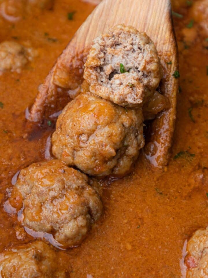 Close up photo of gluten free meatballs on stove top in sauce on large pot