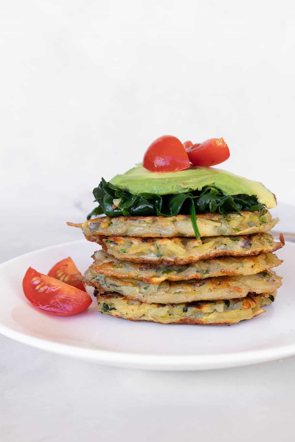 Potato fritters (gluten-free) stacked with spinach, avocado and cherry tomatoes