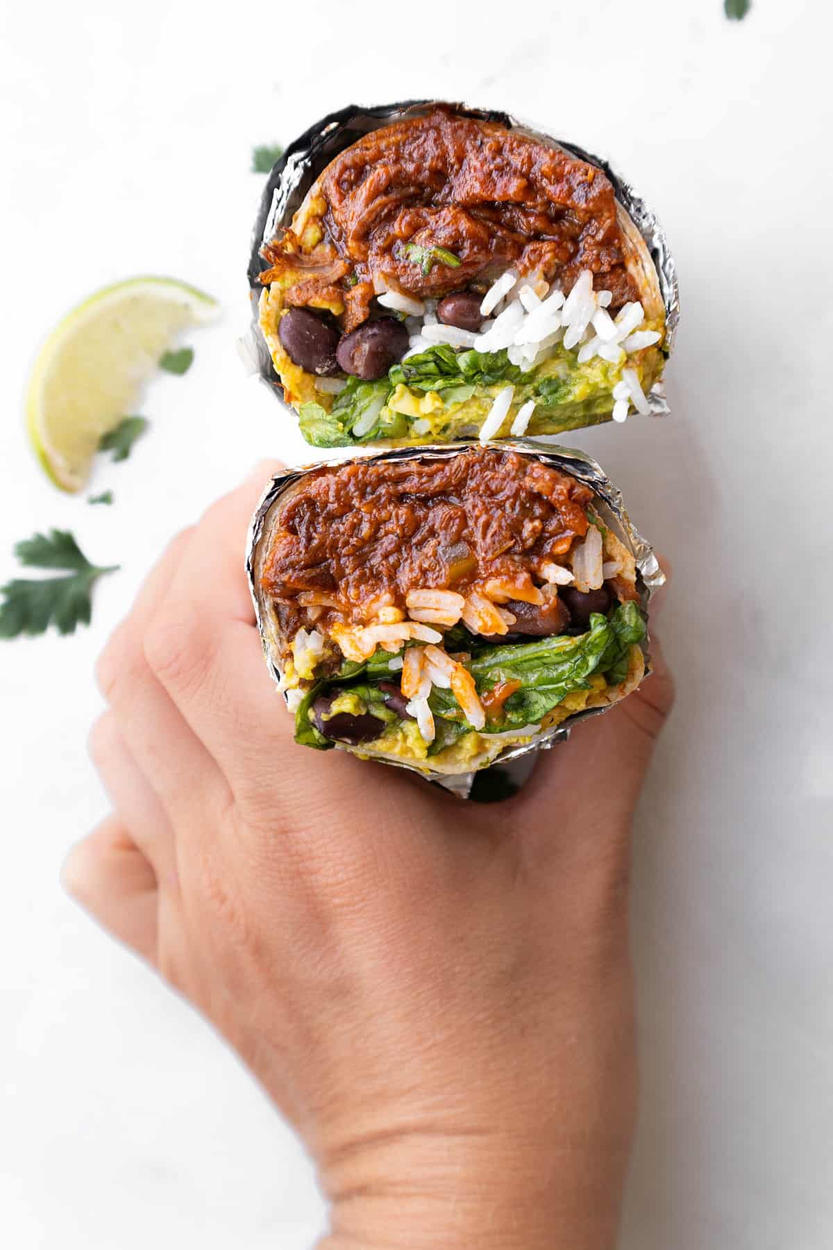 Hand grabbing halved pulled bbq beef burrito