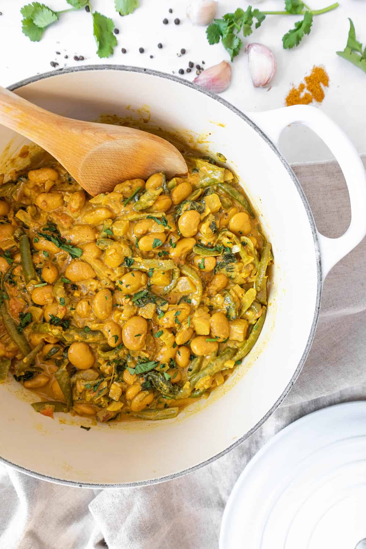 Butter bean curry on a large pot with timber spatula