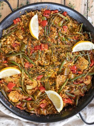 Authentic vegetable paella with lemon wedges