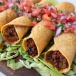 Beef taquitos air fryer on bed of lettuce with pico de gallo on top square