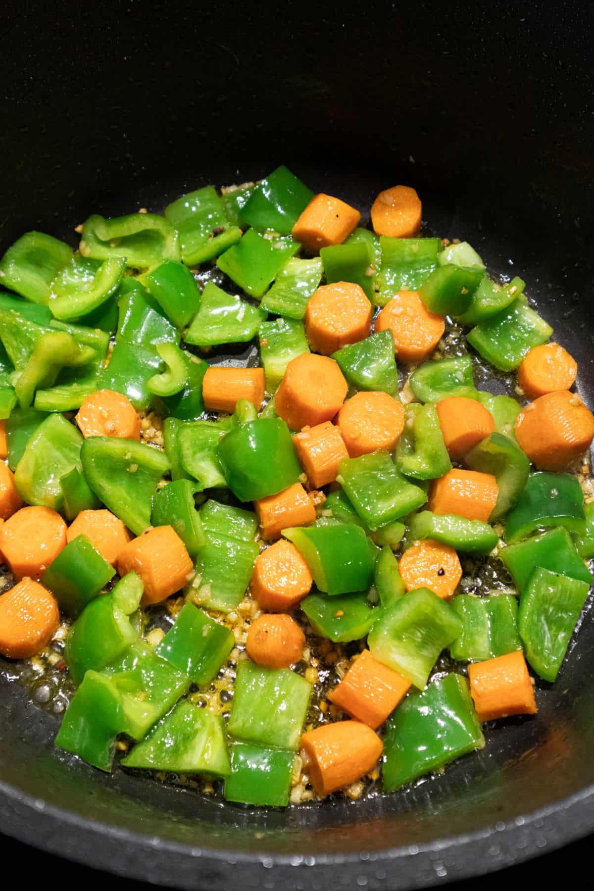 Carrots and green bell pepper cooking on pot