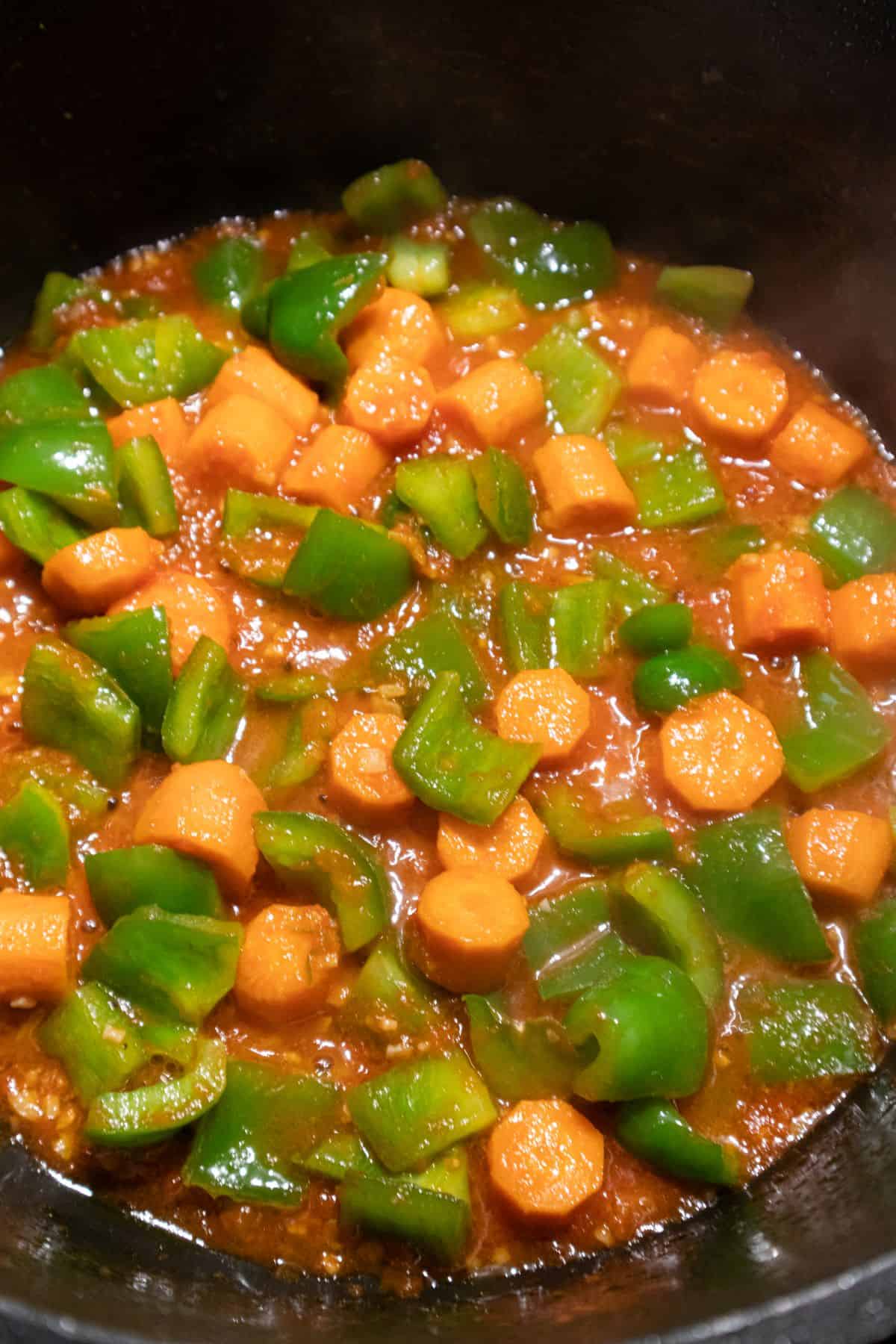 Carrots, green bell pepper and fresh tomatoes cooking on pot